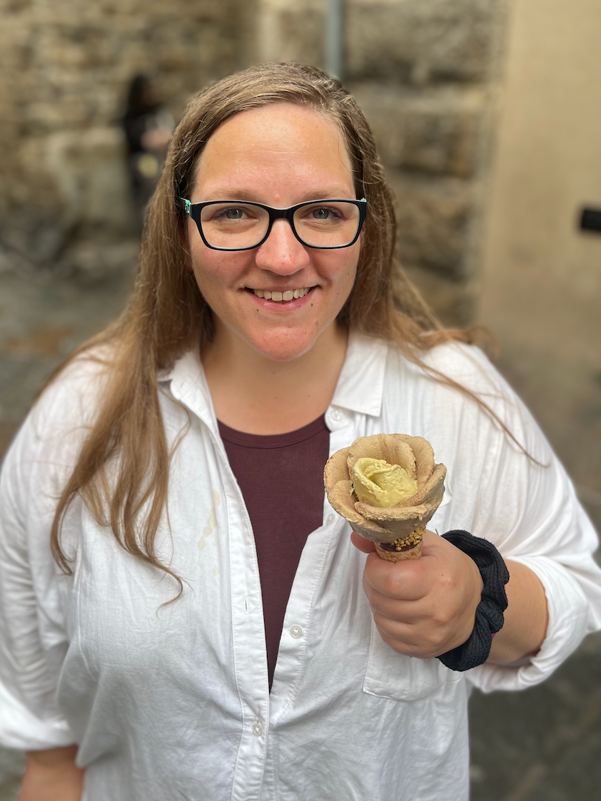 Emily smiling and holding an artisanal gelato in Florence, wearing a white button-down shirt—capturing a joyful moment during real-life family travel in Italy.